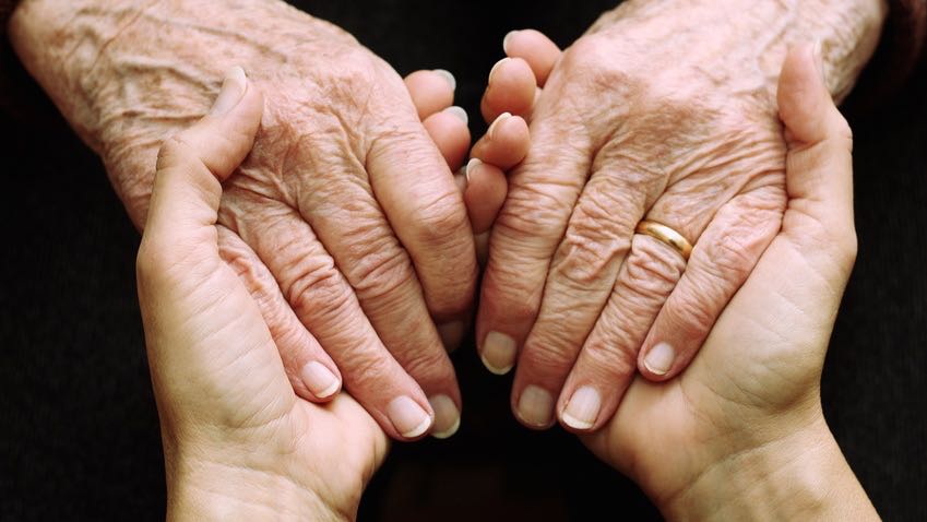 Twee mensen houden elkaars handen stevig vast tijdens de ontmoetgroep kwetsbare ouderen
