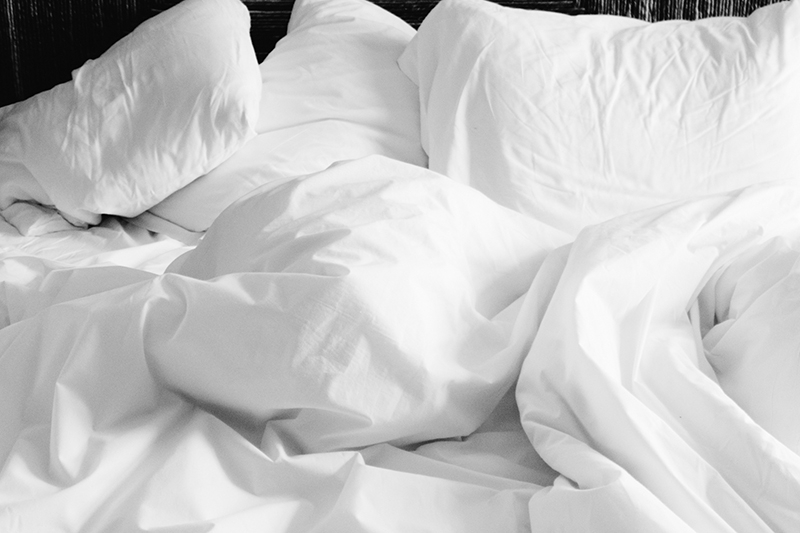 Een bed met witte dekens en kussens