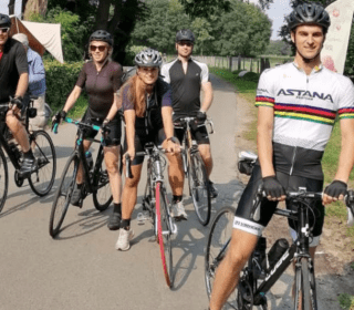 vijf wielrenners met wiel ren kleding staan klaar om te beginnen aan de fietstocht