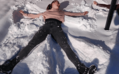 Vrouw met roze trui en zwarte spijkerbroek beweegt in de sneeuw tegen stijve spieren