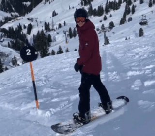 Man op een snowboard in wintersport kleren in een wintersport gebied tips aan het geven om blessures te voorkomen